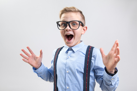 Wow. Waist up portrait of shocked child opening his mouth with pleasant surprise. He is looking at camera and spreading his hands. Isolated on backgroundの写真素材