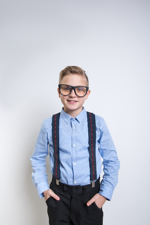 Waist up portrait of fashionable little boy in braces holding his hands in pockets. He is looking at camera with satisfied expression. Isolated on backgroundの写真素材