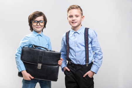 Waist up portrait of dreamful schoolchildren imagining themselves as big bosses. They are looking at camera with satisfaction. Isolated on backgroundの写真素材