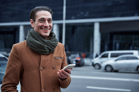Portrait of happy male keeping smartphone. He walking on street. Equipment concept. Copy spaceの写真素材