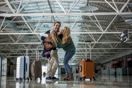 Cheerful parents showing love to their arriving daughter. They are cuddling child closeの写真素材