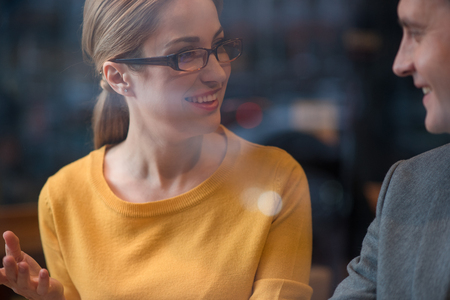 Happy female telling with glad man. She looking at him. Conversation conceptの写真素材