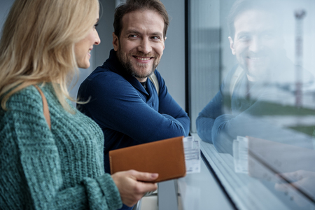 Smiling man is looking at young woman. Lady is holding tickets for the airplane. Copy space in right sideの写真素材