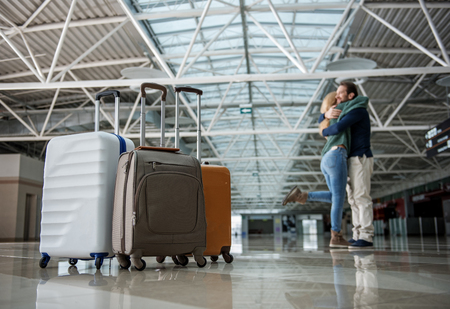 Low angle of two lovers embracing each other after disembarkation. Focus on baggageの写真素材