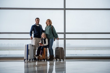 Full length portrait of glad parents and their daughter flying to another country. Copy space in right sideの写真素材