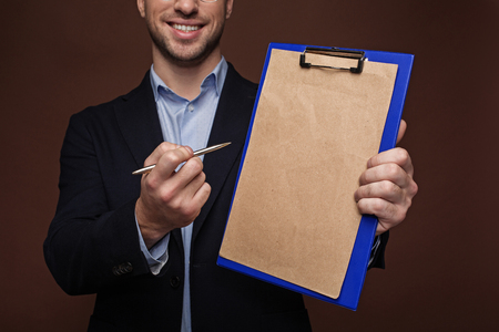 Beaming unshaven man giving clipboard for writing signature on it. Contract conceptの写真素材