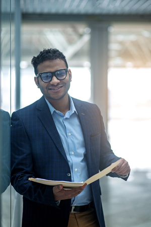Successful businessman. Portrait of cheerful young elegant man is standing with folder of documents. He is looking at camera with joyの写真素材
