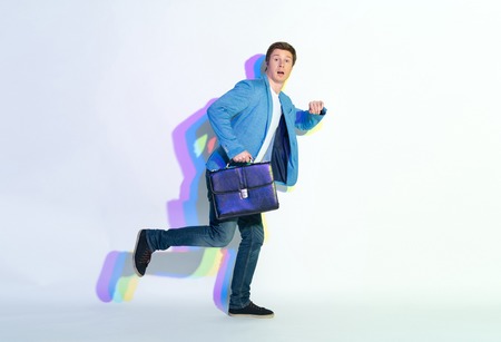 Full length portrait of amazed male hurrying to job. He holding suitcase. Late for labor conceptの写真素材