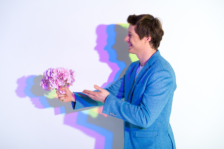 Side view cheerful male stretching hand with beautiful nosegay. He pointing on it. Romance conceptの写真素材