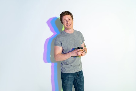 Portrait of cheerful male tasting mug of appetizing coffee. Rest conceptの写真素材