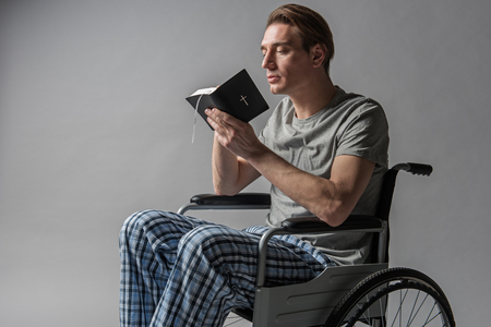 Tranquil invalid with bible turning to god with prayer. Isolated on backgroundの写真素材