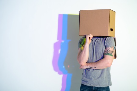 Thoughtful male hiding face inside pasteboard box. Abstraction concept. Copy space