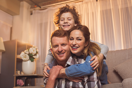 Portrait of outgoing bearded man and beaming lady with smiling boy embracing each other. Leisure conceptの写真素材