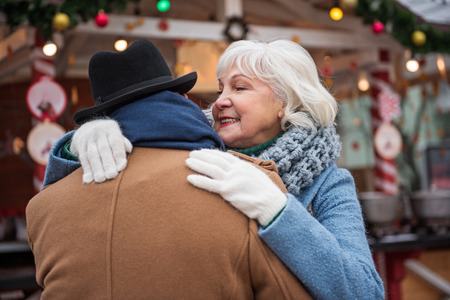 Affectionate mature married couple cuddling while standing outsideの写真素材
