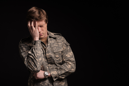 Cheerless male veteran holding his head with hand and frowning. He is feeling terrible and hopeless. Isolated on background. Copy space in right sideの写真素材
