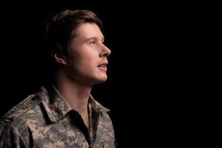 Hopeful military man looking up with belief. Concept of hope. Isolated on background. Copy space in right sideの写真素材