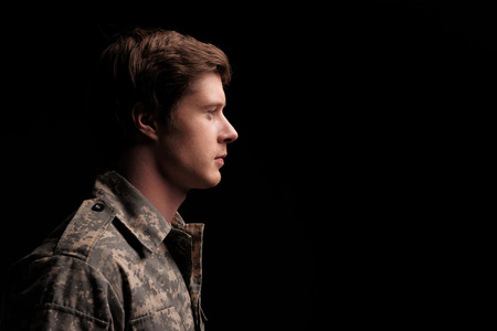 Serene male cadet looking thoughtful and hopeful. He is standing turned in profile. Isolated on background. Copy space in right sideの写真素材