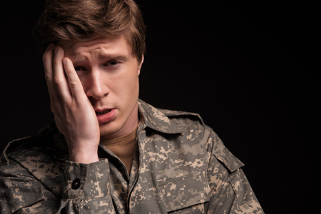 Portrait of despondent male officer looking at camera and standing with unhappy look. Concept of sadness. Isolated on backgroundの写真素材