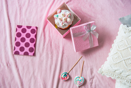 Top view Easter cake in pink box locating near copybook and candies on carpet. Holiday conceptの写真素材