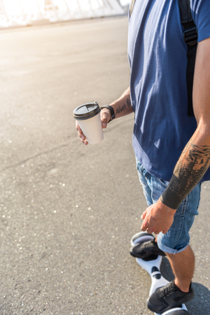 Top view close up arm male keeping cup of delicious tea while driving on gyroscooterの写真素材