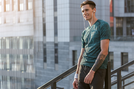 Side view cheerful man listening music while running outdoor. Copy spaceの写真素材