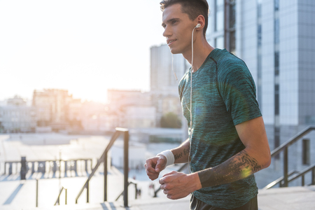 Side view cheerful man listening music while running outdoor. Copy spaceの写真素材
