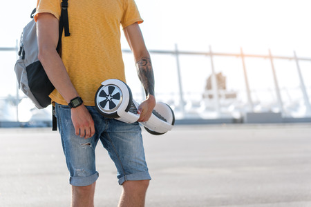 Close up young man hand holding new gyroboard in hand while walking at street. Copy spaceの写真素材