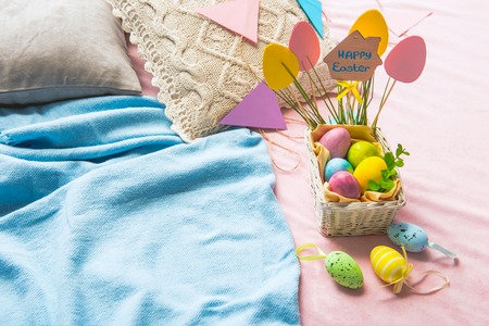 Top view basket with colored eggs locating on pink floor near blue plaid. Easter concept