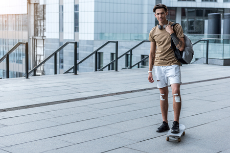 Full length portrait of cheerful young man riding on skate at streetの写真素材