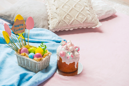 Delicious easter bread situating near basket with colored eggs situating on carpet. Holiday concept