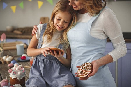Satisfied mother and daughter embracing and admiring their handmade confection indoors