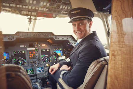 Portrait of cheerful male aviator in uniform sitting in cockpit. Job conceptの写真素材