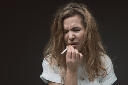 Portrait of woman inhaling coffin nail fume and expressing dissatisfaction. Copy space in left side....
