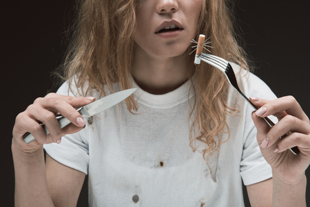 Peaceful woman holding knife and fork with prickly cigarette end on it. Isolated on backgroundの写真素材