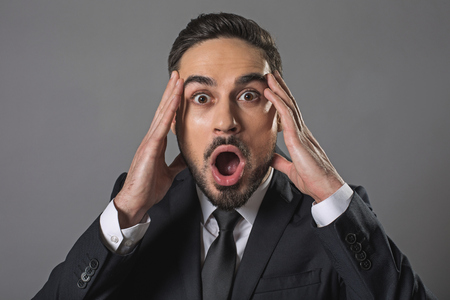 I am terrified. Waist up portrait of surprised man getting some incredible news. Isolated on grey backgroundの写真素材