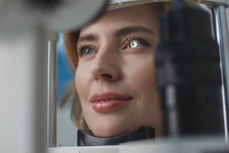 Close up beaming woman face inspecting eyes in ophthalmological center. Medicine concept