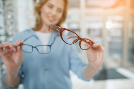 Close up female hands keeping spectacles in optical store. Ophthalmology conceptの写真素材