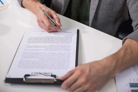 Great deal. Close up of male hands underwriting documents with penの写真素材