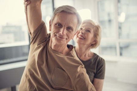 Portrait of glad slim pensioner with raised arm. Smiling senior woman on background holding his arm. Focus on manの写真素材