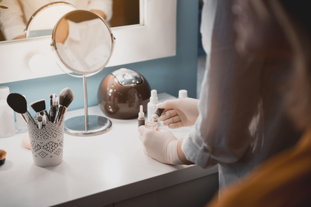 Close up female worker arms blending cosmetic substance. She standing near desk with it. Skin care conceptの写真素材