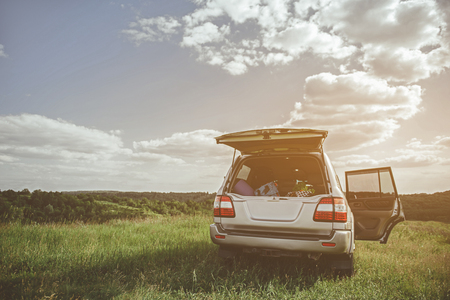 Touristic equipment in trunk of car on summer meadow. Family trip concept. Copy spaceの写真素材