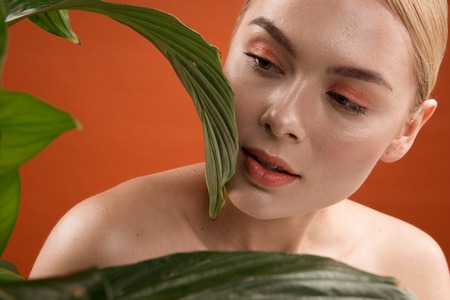 Natural female look. Portrait of appealing girl with daily maquillage near fresh leaves. Isolated on backgroundの写真素材