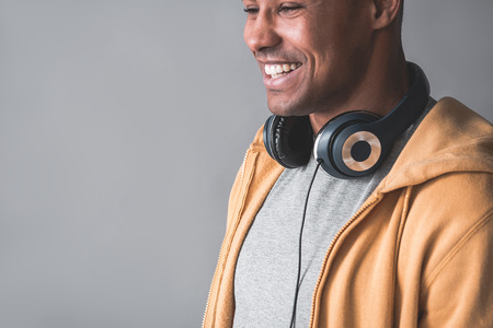 Glad student in sports jacket wearing headsets on neck. He is looking aside and laughing. Copy space in left side. Isolated on backgroundの写真素材
