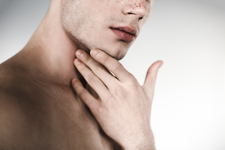 Serious undressed male holding chin by hand. He having freckles on nose. Earnest concept. Close upの写真素材