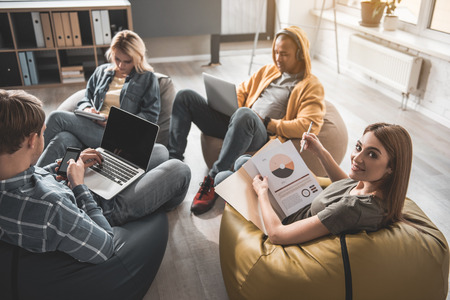 Tranquil men and women sitting with comfort in their modern office. Girl with project documentation...