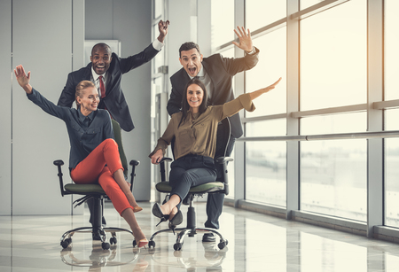 Full length portrait of beaming colleagues having fun while creating friendly competition in office. Cheerful partners relaxing at work conceptの写真素材