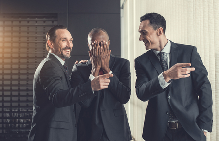 Outgoing colleagues communicating while flourishing arms. Male closing face by hand. Positive during job conceptの写真素材