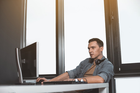 Side view focused programming specialist using modern computer. Interested worker at labor with...