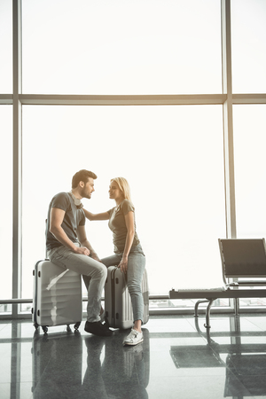 I love you. Full length side view outgoing woman talking with cheerful man. They sitting on baggages. Glad couple conceptの写真素材
