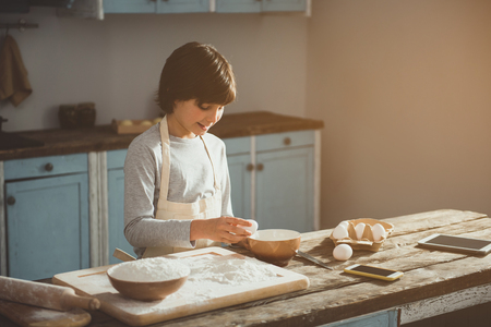 Enjoyed child cooking bakery at home. He is smashing an egg. Copy space in right sideの写真素材